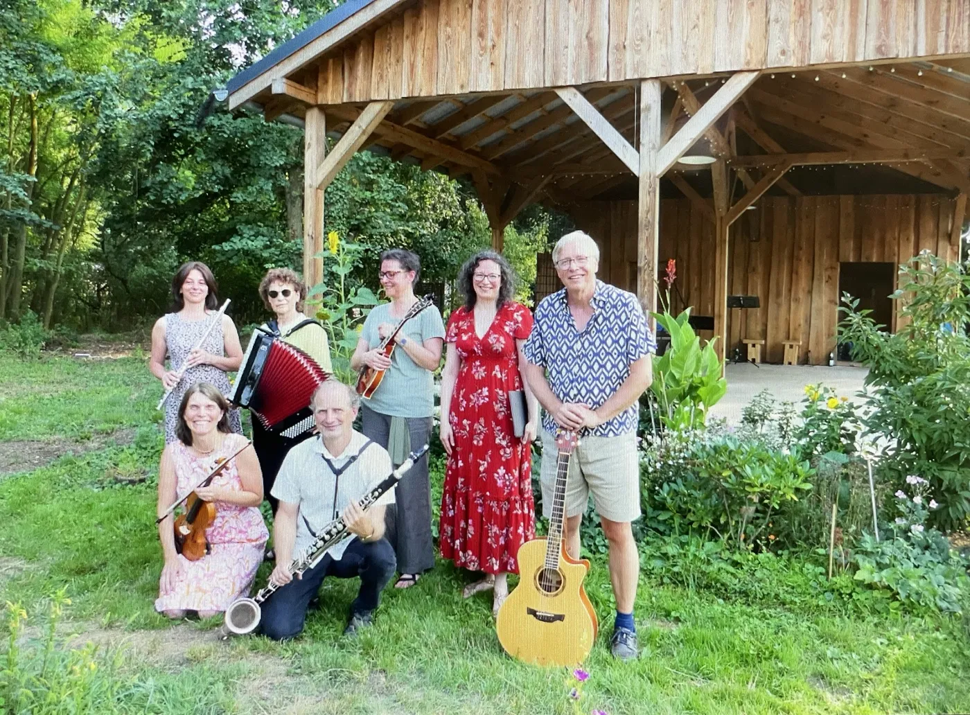 Die Balfolk Band Antanjo mit Karin Stein im roten Kleid vor einer Holzbühne im Garten